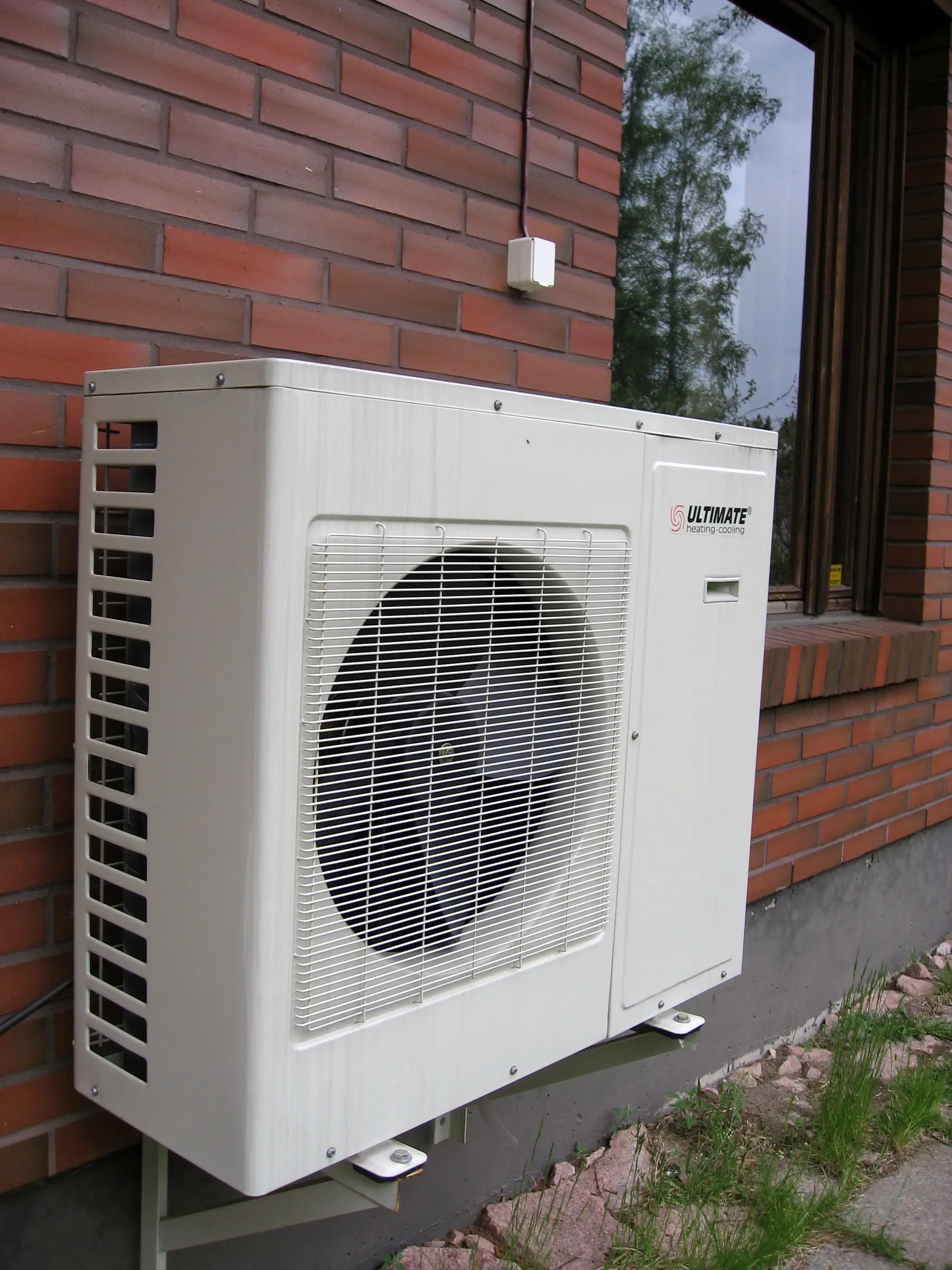 Air source heat pump outdoor condenser unit beside a house
